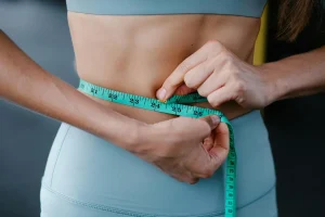 Woman measuring waist as part of semaglutide weight loss treatment