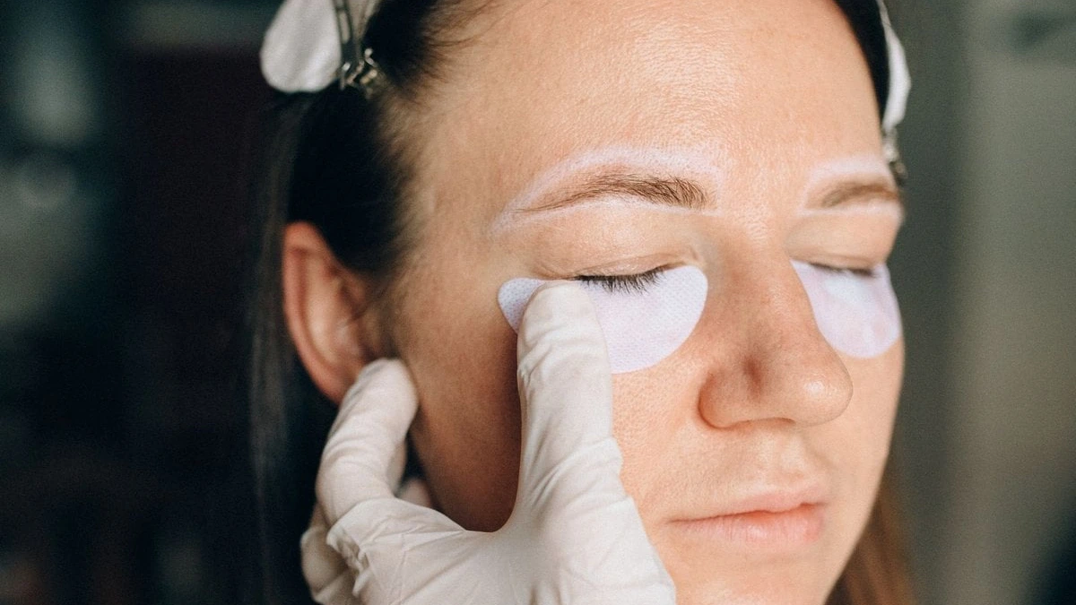 Gloved hands placing under-eye patches on a model